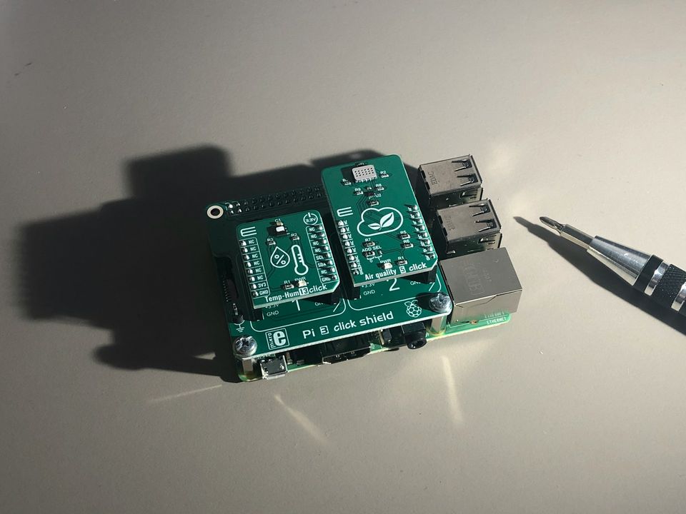 Raspberry Pi с подключённым Pi E click shield и датчиком температуры/влажности для сборки погодной станции. Рядом лежит отвёртка для настройки. Идеально для DIY-проектов умного дома.